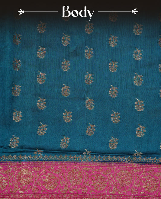 Teal colour pure tussar Banaras silk saree featuring intricate gold zari motifs across the body, enhanced with a contrast Magenta floral kodi zari border for a rich traditional look. Comes with a matching blouse piece.