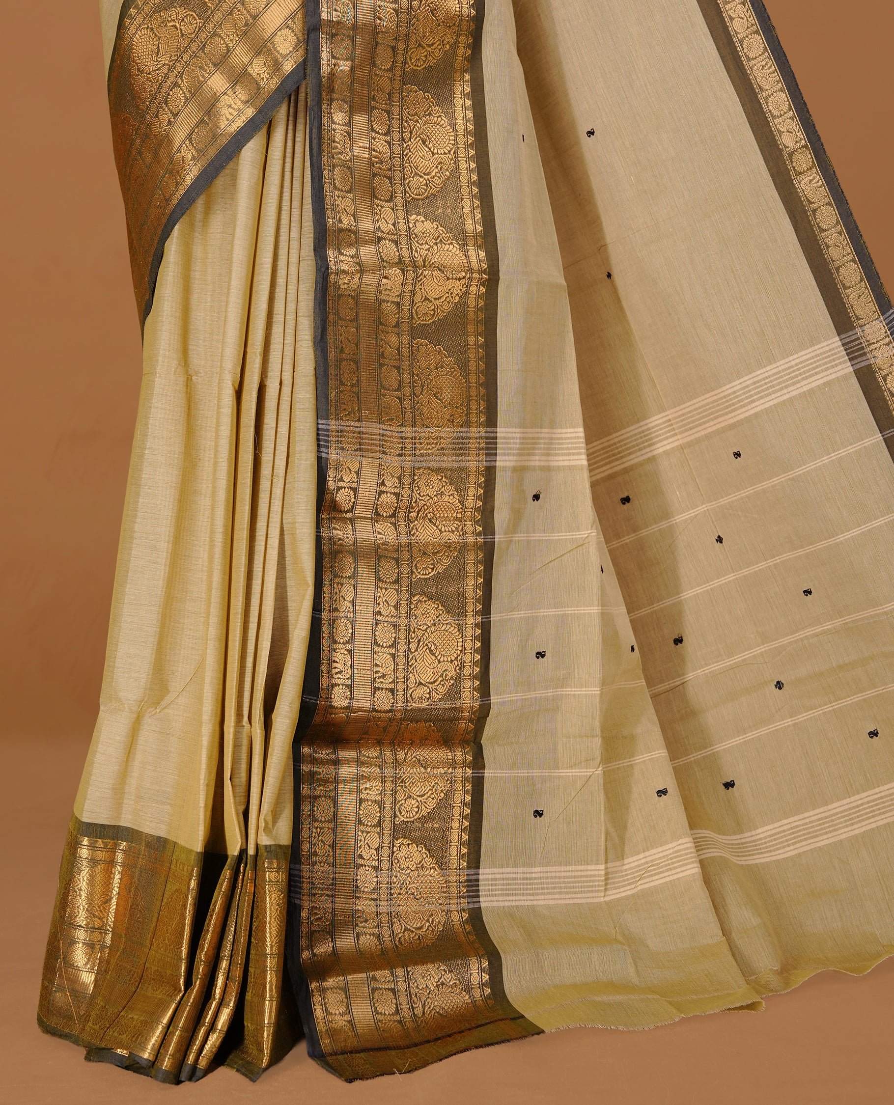 Greyish cream colour Chettinad cotton saree featuring motifs body, complemented by contrast Black colour with gold zari border, paired with matching blouse piece.