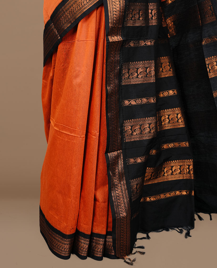 Orange colour kalyani cotton saree featuring antique zari motifs on body, complemented by black colour with Antique zari border, paired with matching blouse piece.