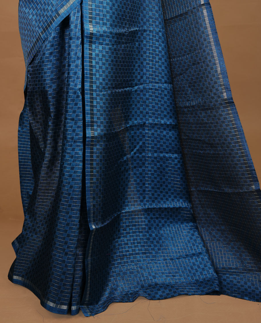 Peacock blue colour Semi Tussar saree featuring an elegant zari fancy check pattern on the body, highlighted with a small border for a refined look. Comes without a blouse piece.