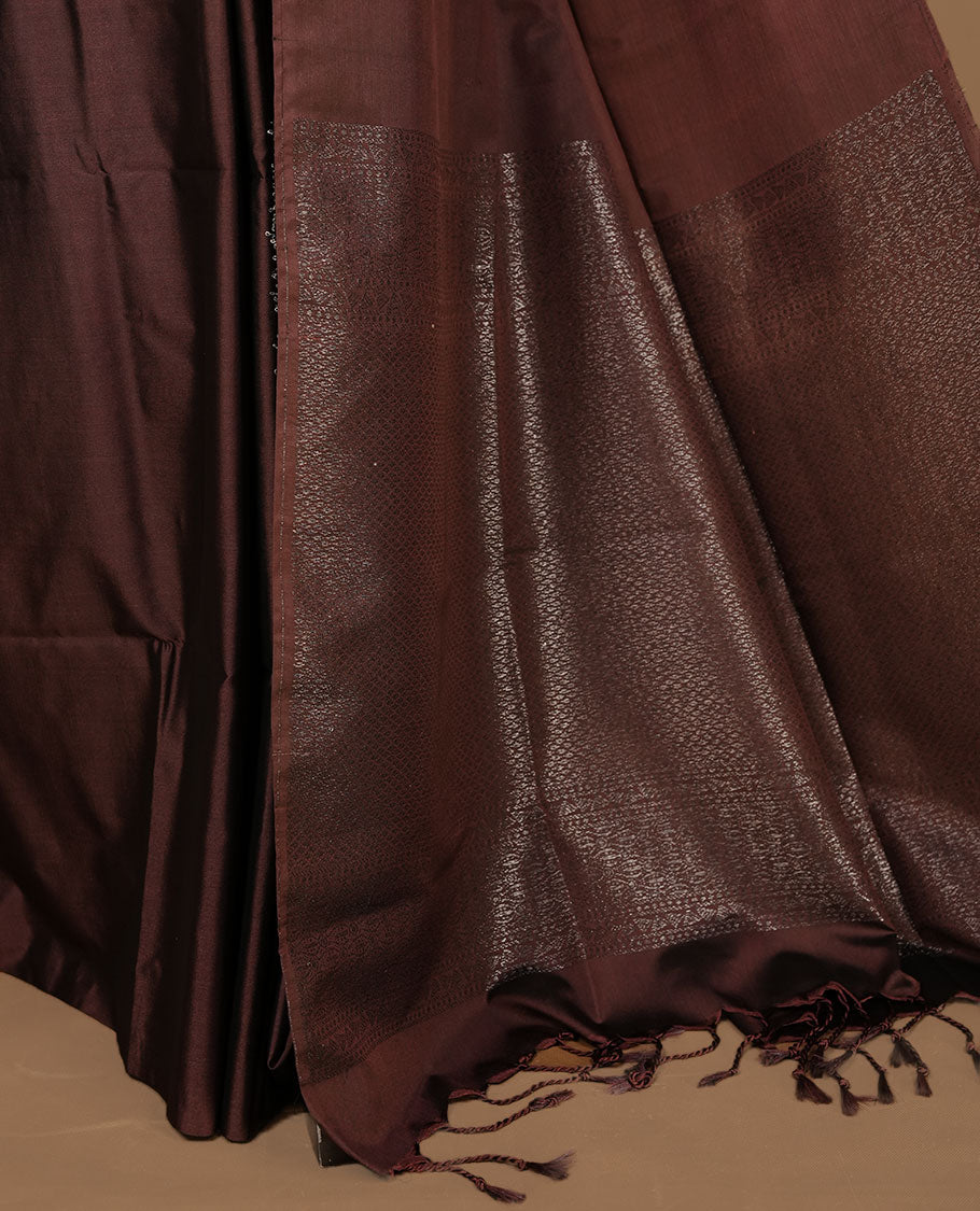 Chocolate soft silk saree features a sleek borderless design with intricate antique zari motifs, flowing into a seamless self colored pallu and a matching blouse piece.