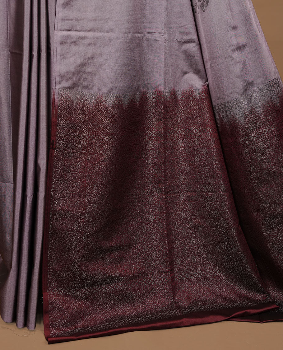 Lavender colour soft silk saree features a sleek borderless design with intricate antique zari motifs, flowing into a striking contrast maroon pallu and a matching blouse piece.