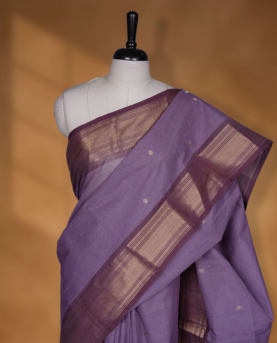 Dark lavender colour chettinad cotton saree featuring small gold zari buttas on body highlighting contrast magenta purple colour with gold zari traditional border, pallu and paired with matching blouse piece.