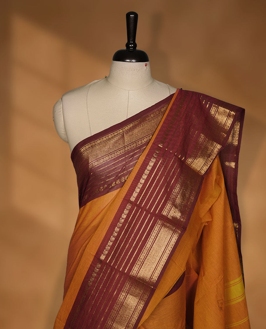 Orange colour chettinad cotton saree featuring plain body, contrast burgundy colour with traditional gold zari border paired with matching blouse.