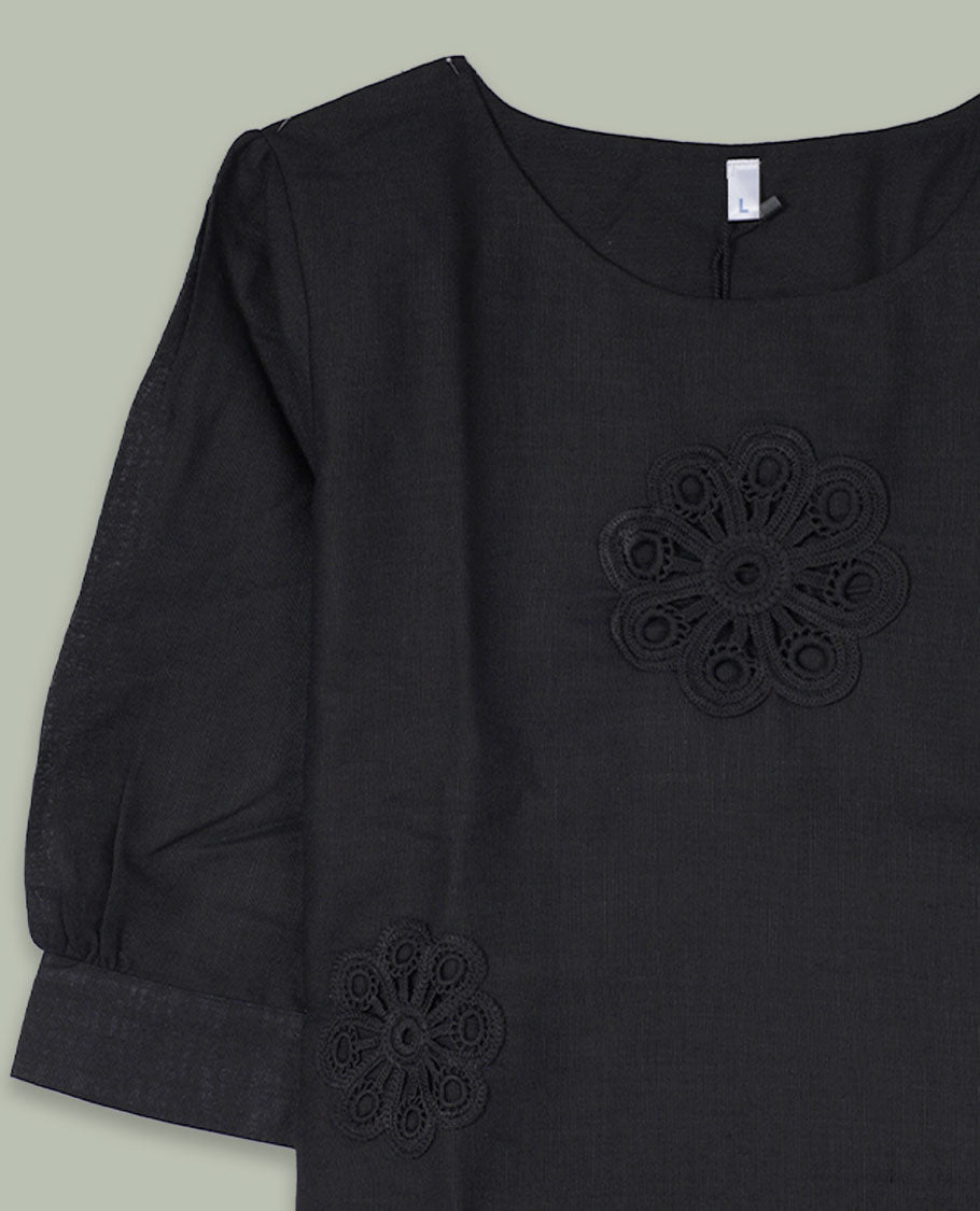 Black three-quarter sleeve top with round neckline and tonal crochet floral appliqués placed at the center front and near the hem.