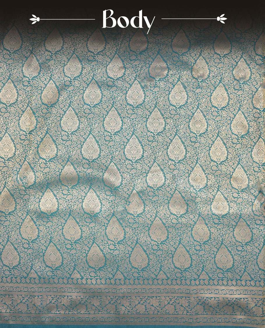 Teal blue colour semi silk brocade saree featuring intricate Gold Floral kodi patterns across the body, complemented by a Self colour woven border and pallu, paired with a matching blouse.