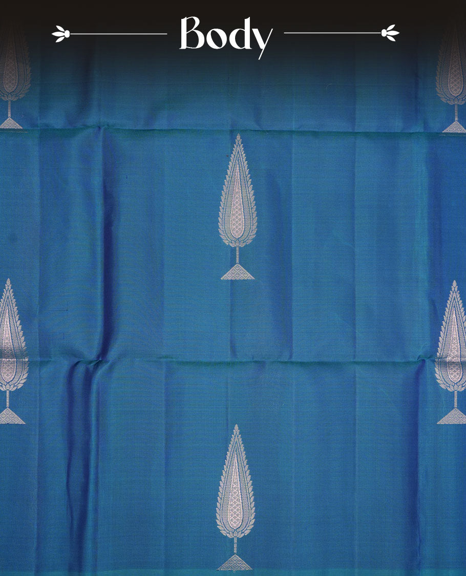Peacock colour soft silk saree featuring silver zari motifs on body, complemented by self colour with traditional border with tassel at pallu, paired with matching blouse piece.