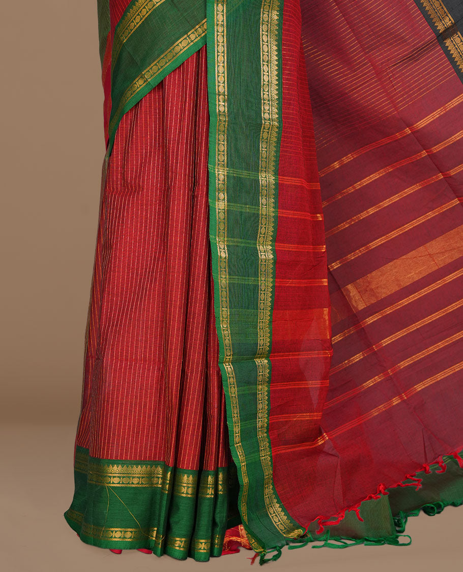 Maroon colour chettinad cotton featuring gold zari check pattern on body , complemented by contrast Green colour with gold zari border, paired with matching blouse piece.