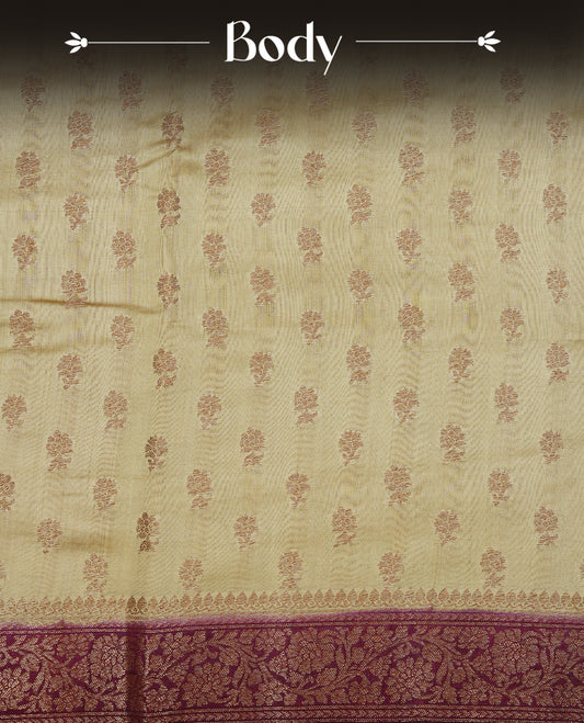 Cream colour pure tussar Banaras silk saree featuring intricate gold zari motifs across the body, enhanced with a contrast Maroon floral kodi zari border for a rich traditional look. Comes with a matching blouse piece.
