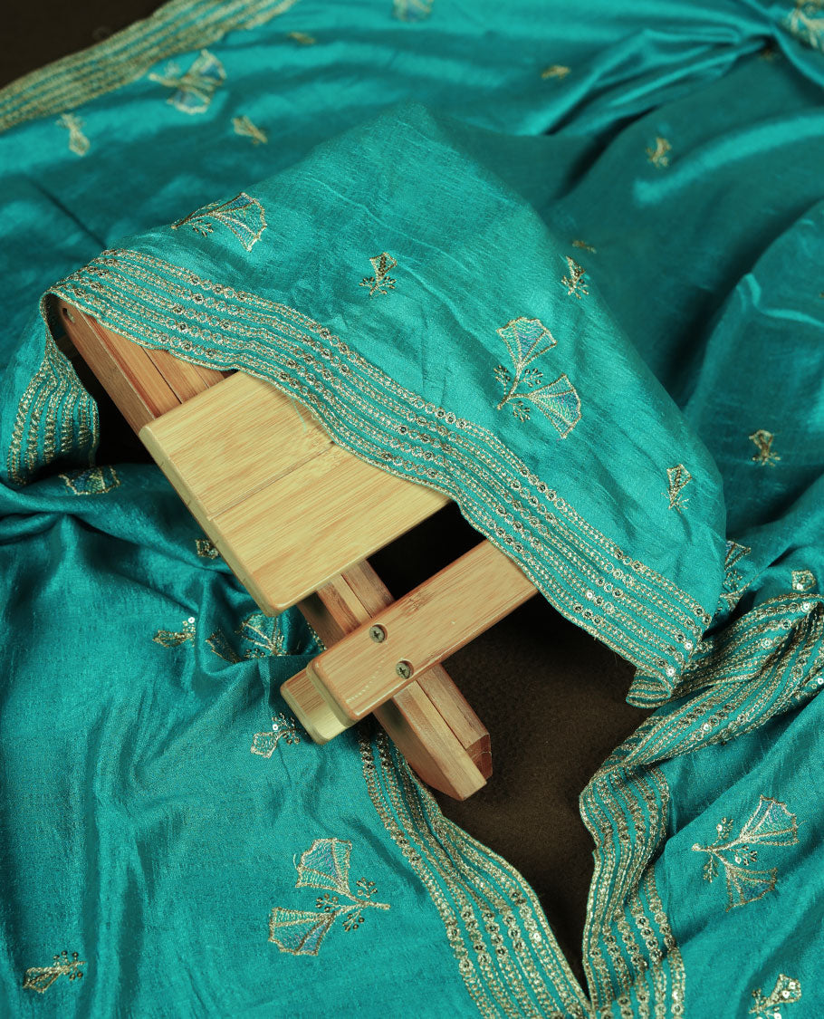 Teal colour churidar material with subtle mirror and thread embroidery, finished with delicate border detailing and paired with a matching plain bottom and dupatta.