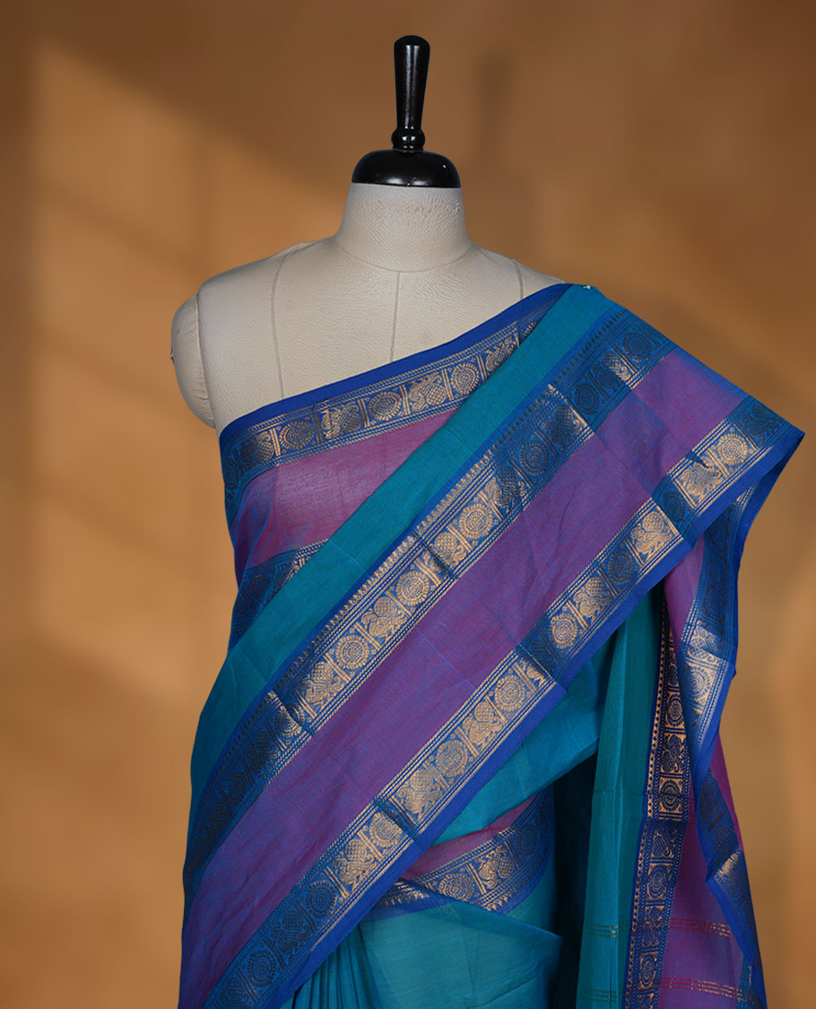 Aqua lake colour chettinad cotton saree featuring elegant plain body highlighting contrast magenta and blue colour with gold zari Peacock border, pallu and paired with matching blouse piece.