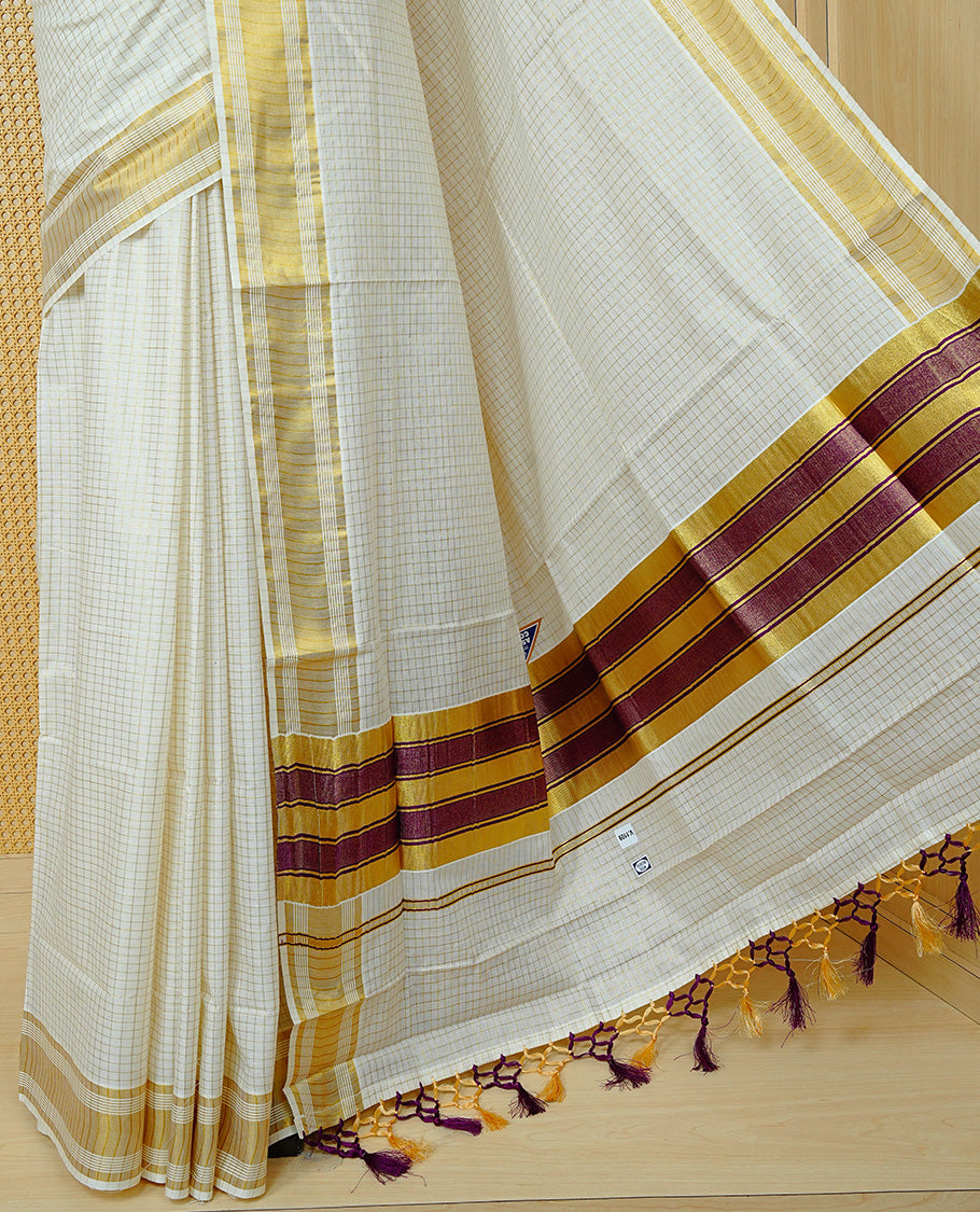 Cream colour Cotton kerala saree featuring Gold zari Checks on body, complemented by Gold zari border & Purple with gold zari on Pallu, paired with matching blouse piece.