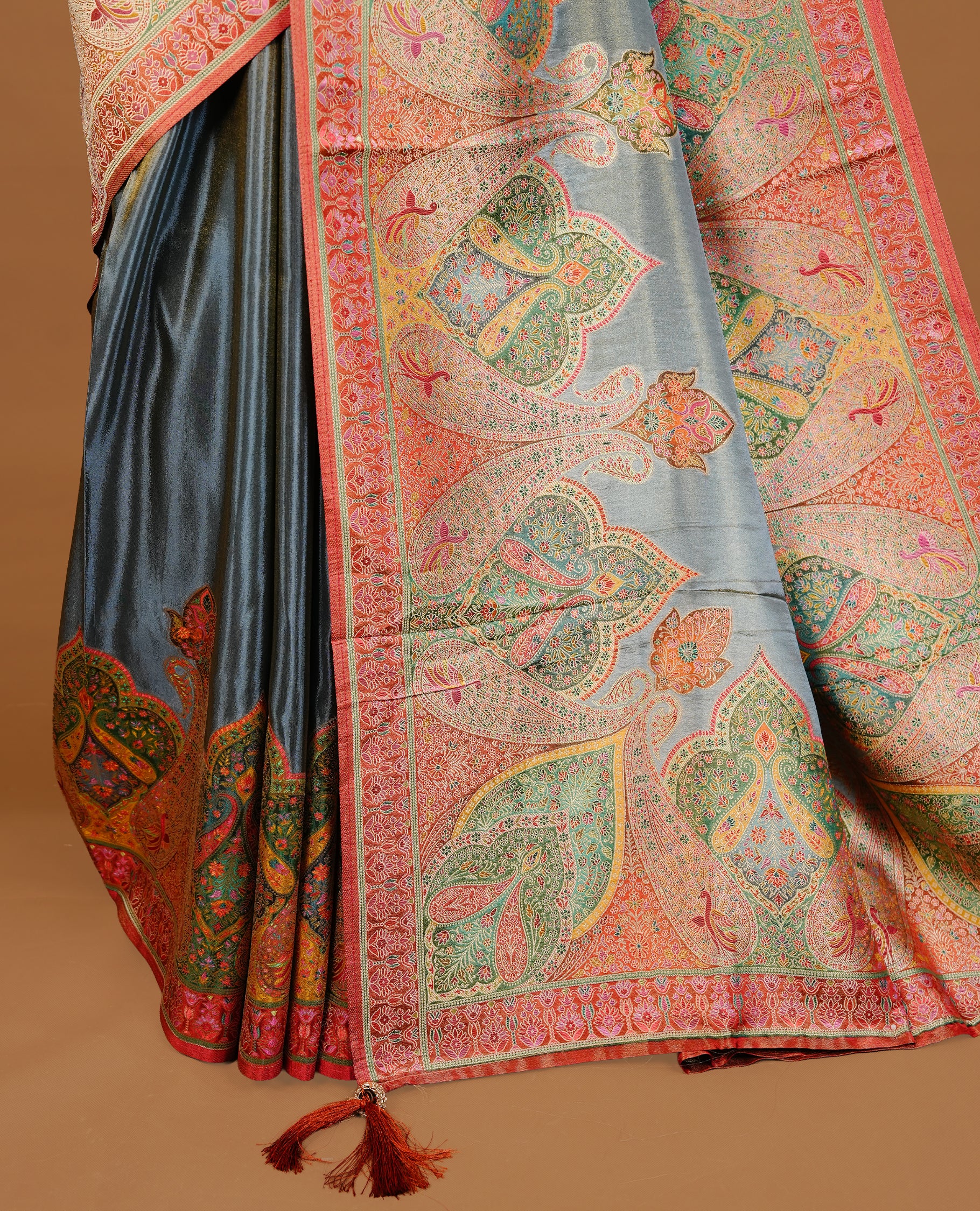 Grey colour Pashmina Saree featuring a plain lustrous body, a multicolour traditional woven border, a rich traditional woven pallu with intricate paisley motifs, paired with a matching grey blouse.