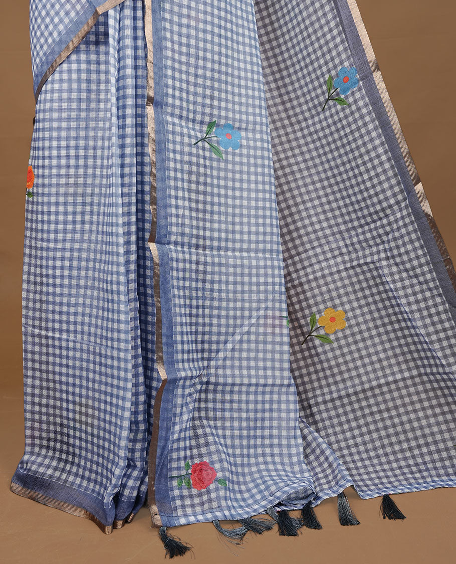 Grey colour Semi Linen saree featuring a stylish check pattern adorned with floral prints on the body, enhanced by a small gold border, paired with a matching blouse piece.