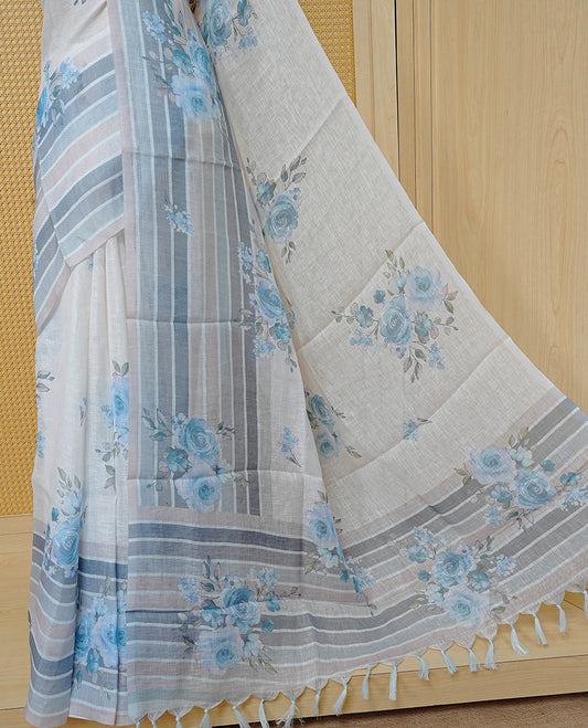 Cream colour semi linen saree featuring Blue colour floral print on body, complemented by contrast Strip pattern border, comes with matching blouse piece.