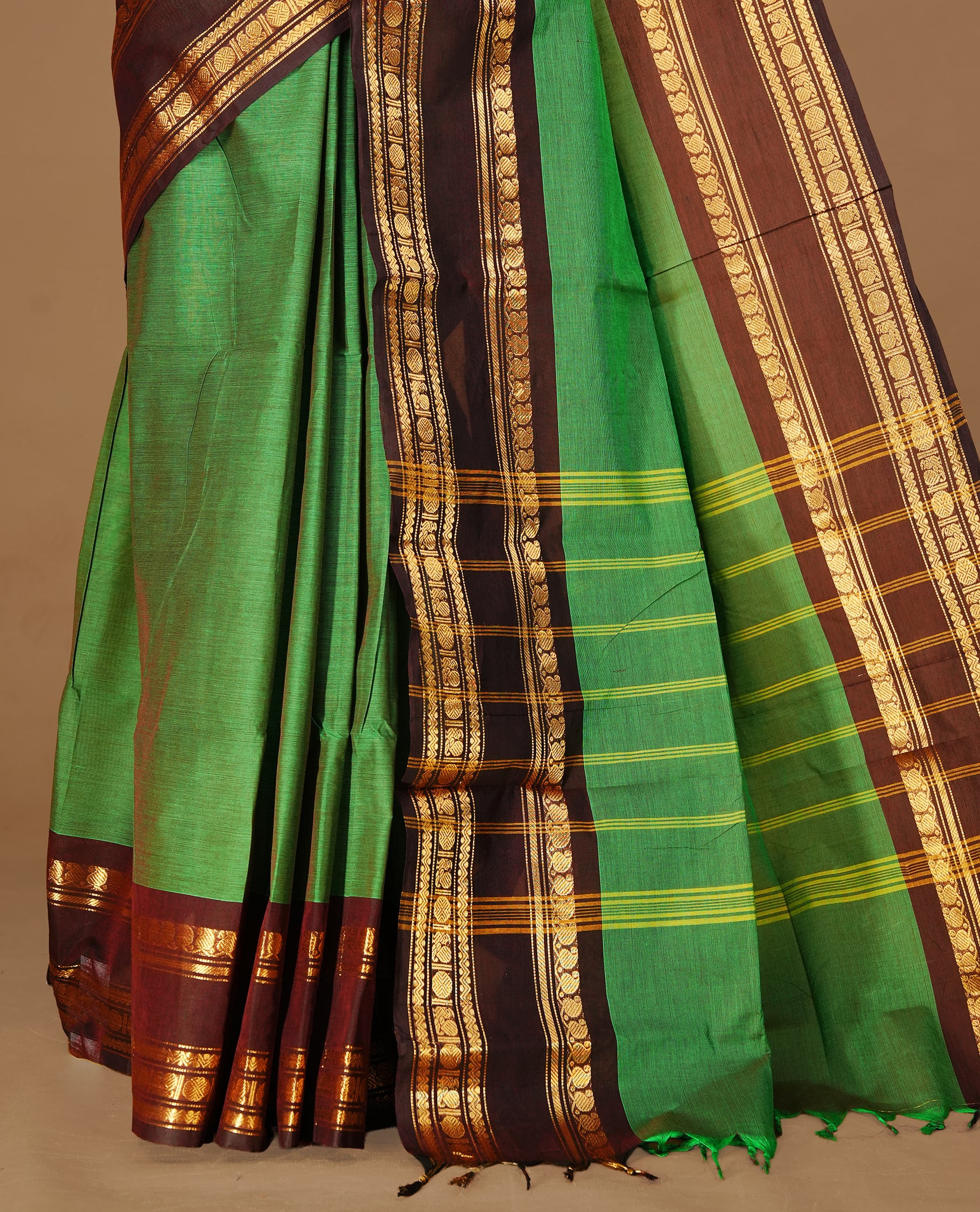 Green colour Chettinad cotton saree featuring Elegant plain body, complemented by contrast Chocolate Brown colour with gold zari border, paired with matching blouse piece.