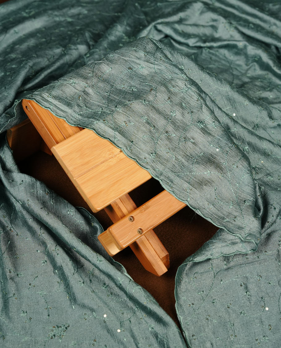 Ivory colour churidar material with teal colour thread embroidery on the front panel, paired with a matching dupatta and bottom.