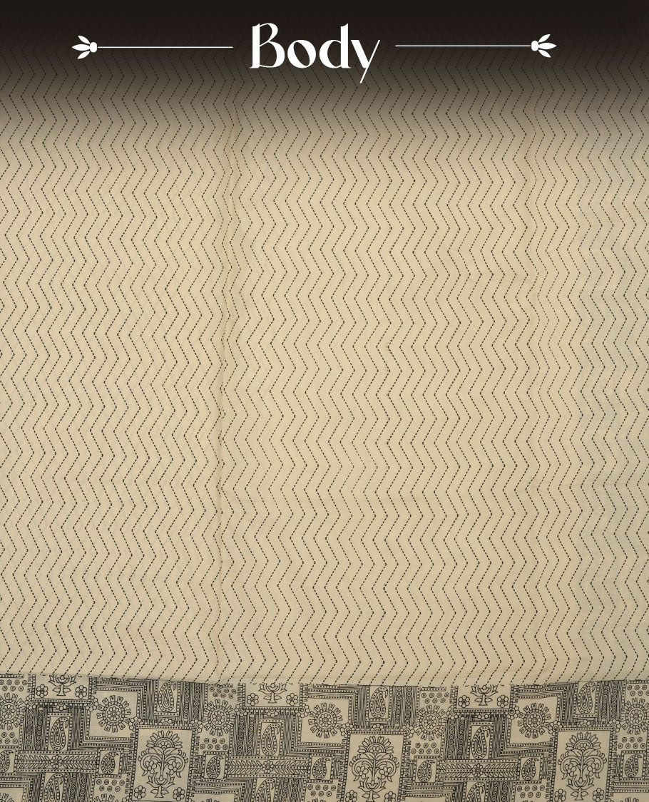 Cream colour poly cotton saree with black zigzag line pattern on the body, paired with a matching pallu featuring black chevron lines and panelled floral‑paisley design, and a coordinated all‑over floral paisley patch‑style printed blouse piece.