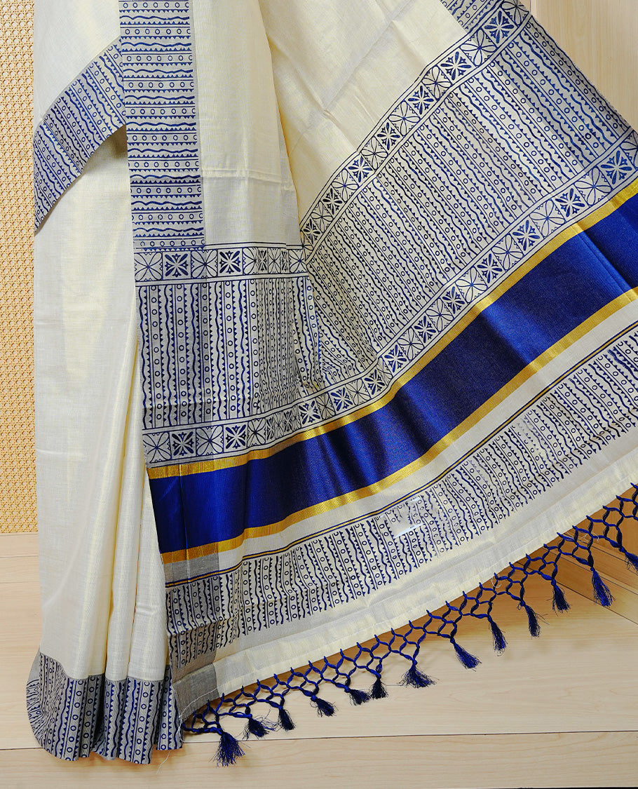 Cream Colour Tissue Kerala Saree Featuring Blue Geometric Digital Prints Along the Border, Enhanced with a Royal Blue and Gold Zari Border, Traditional Printed Pallu, Finished with Blue Tassels and a Matching Blouse Piece