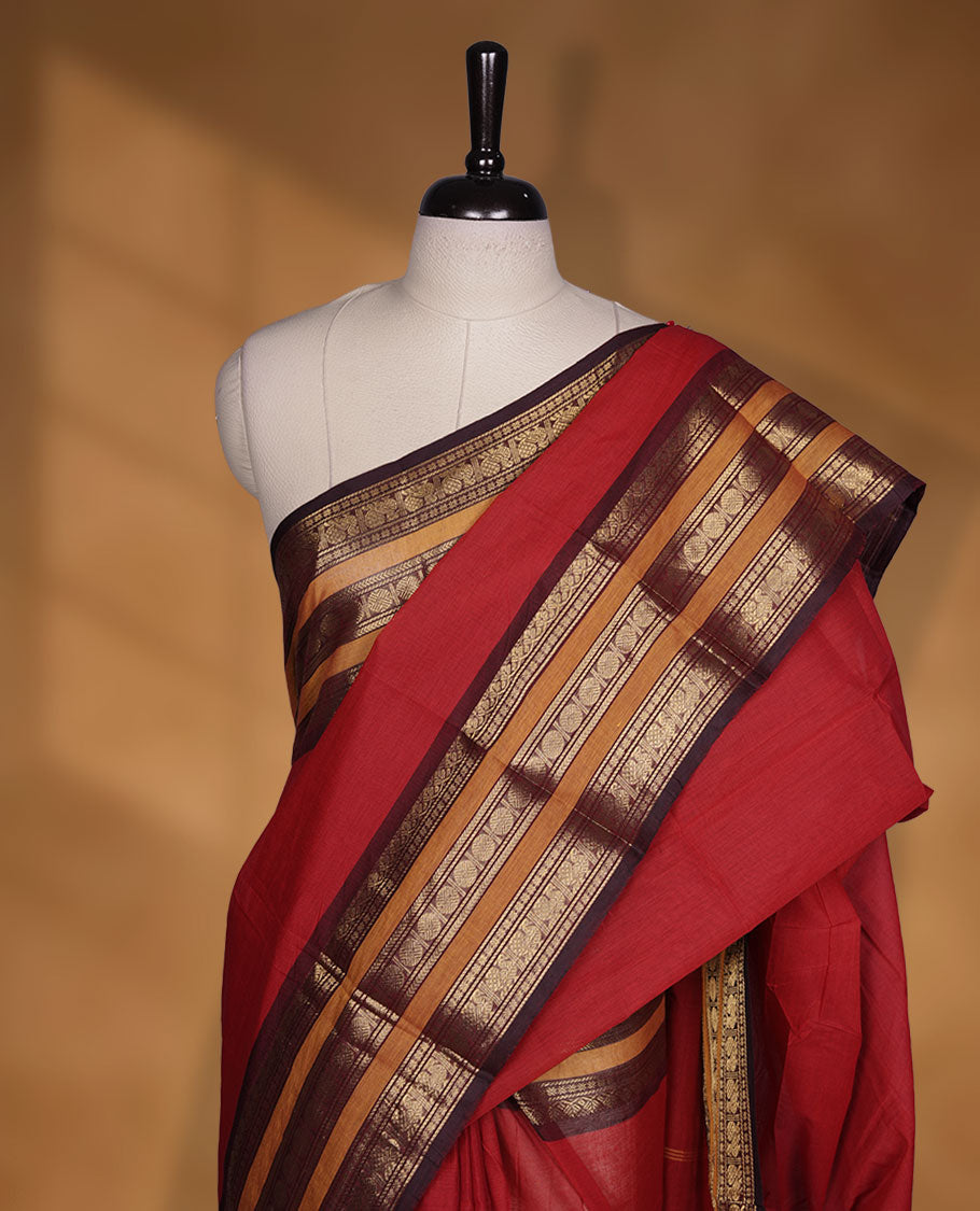 Red colour chettinad cotton saree featuring plain body, contrast chocolate brown and mustard colour with traditional gold zari border paired with matching blouse.