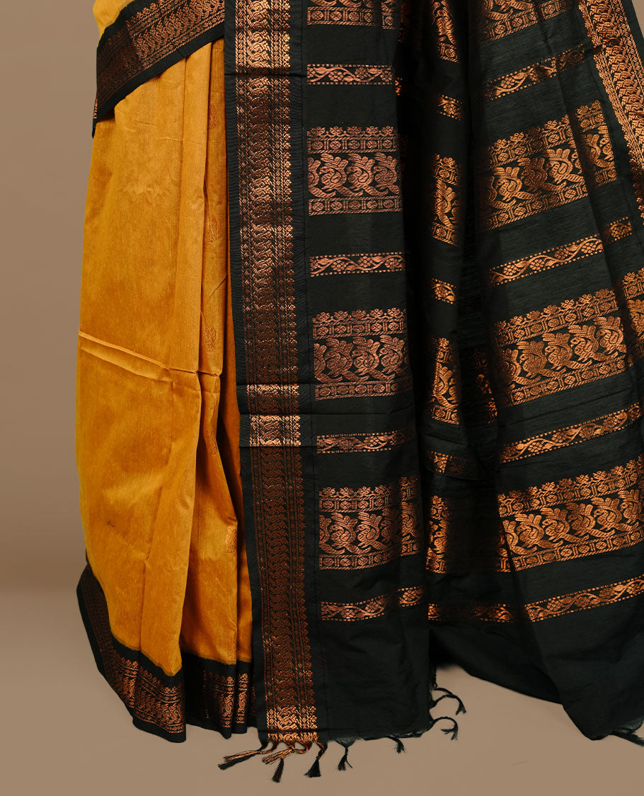 Mustard colour kalyani cotton saree featuring Elegant plain body, complemented by Black colour with Antique zari border, paired with matching blouse piece.