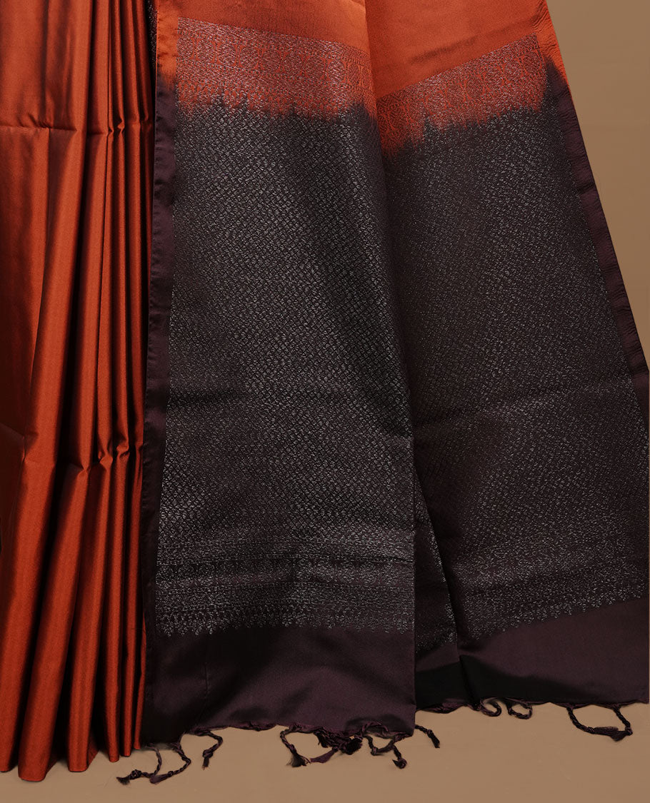 Rust orange colour soft silk saree features a sleek borderless design with intricate antique zari motifs, flowing into a striking contrast Black berry pallu and a matching blouse piece.