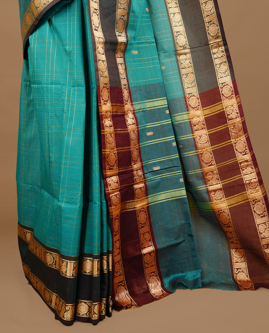 Teal colour chettinad cotton saree featuring gold zari motifs & check pattern on body, complemented by green colour with zari border, paired with matching blouse piece.