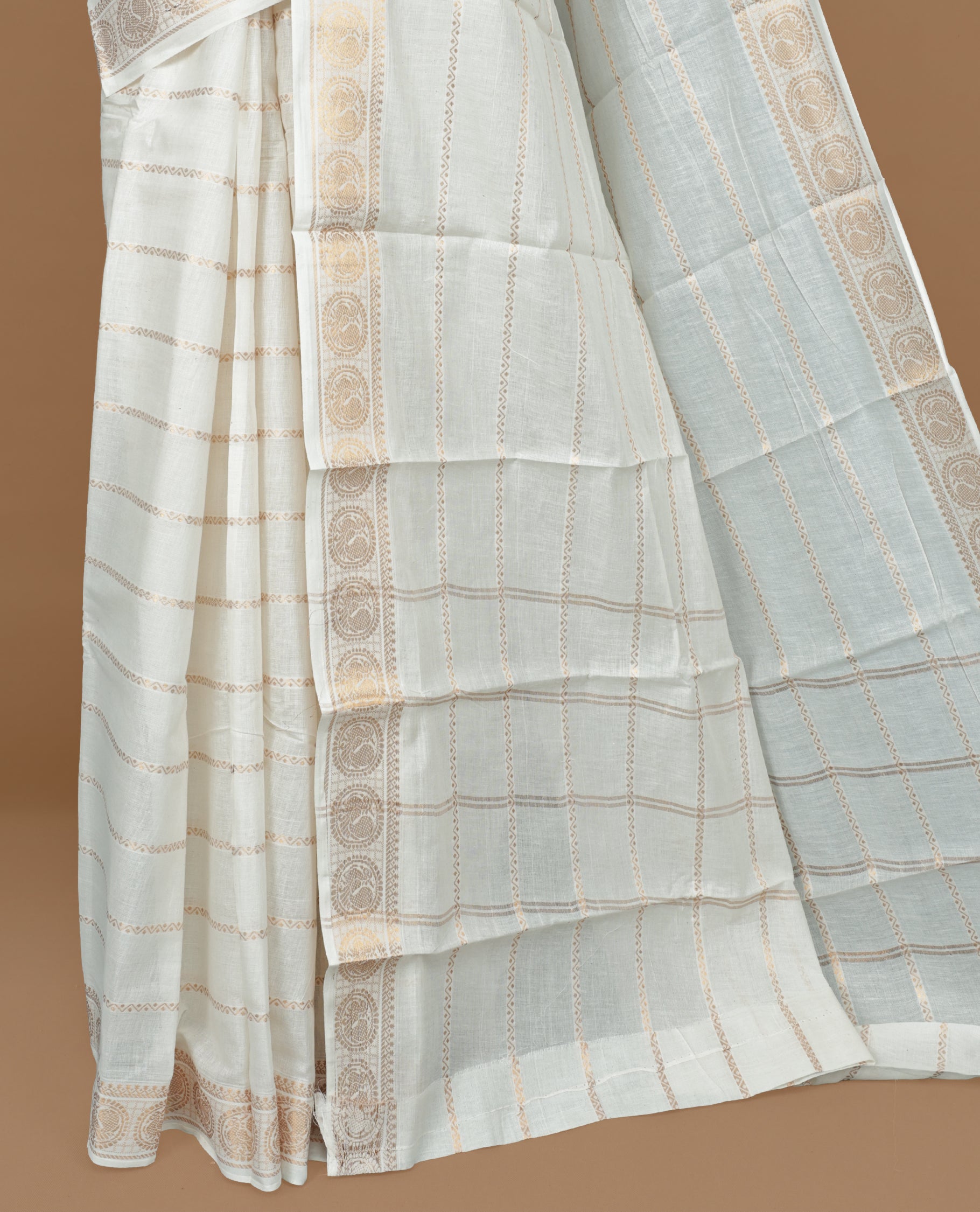 Off white colour Sungudi cotton saree featuring Gold zari Zigzag stripes on body, Gold zari Peacock chakram design on Self colour border, paired with matching blouse piece.