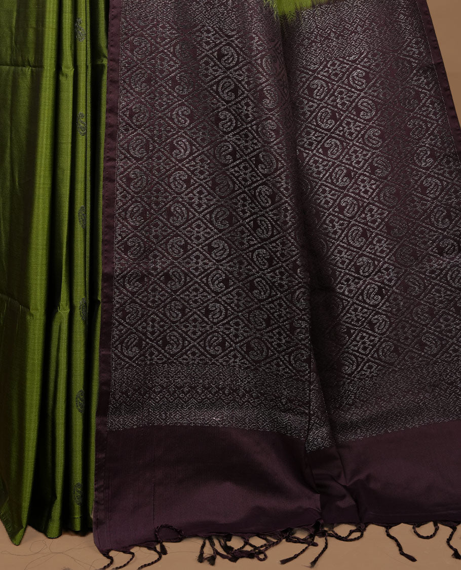Olive colour soft silk saree features a sleek borderless design with intricate antique zari motifs, flowing into a striking contrast deep purple pallu and a matching blouse piece.