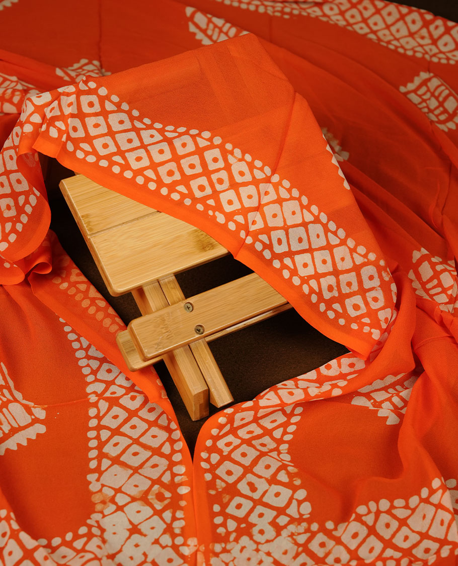 Bright orange colour churidar material featuring elegant gold butta work on the front panel, paired with a printed dupatta and matching bottom.