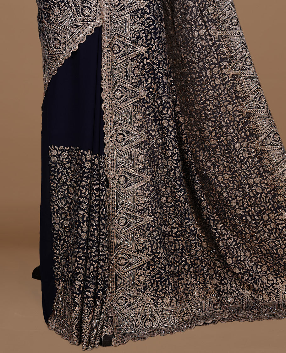 Dark blue colour georgette designer saree featuring Gold thread floral pattern on body highlighting with stone and scalp border, paired with matching blouse piece.