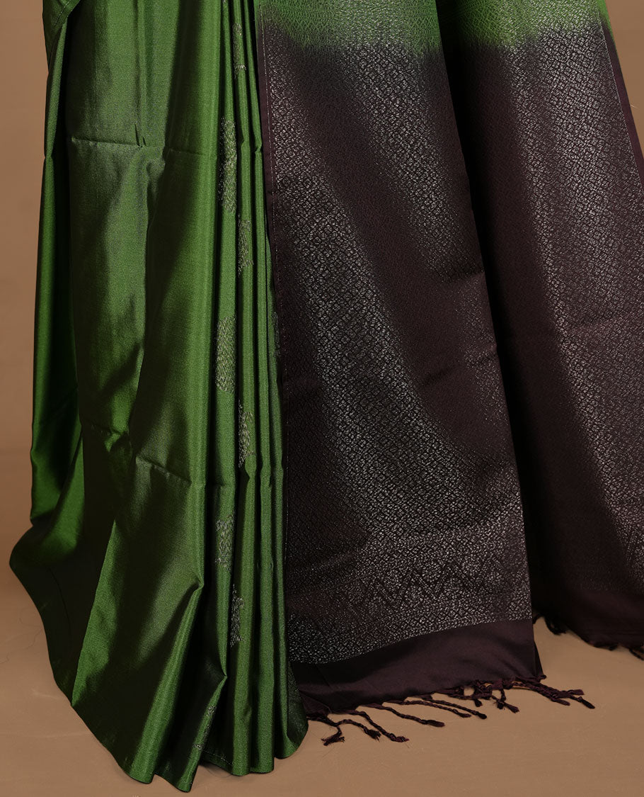 Green colour  soft silk saree features a sleek borderless design with intricate antique zari motifs, flowing into a striking contrast chocolate brown pallu and a matching blouse piece.