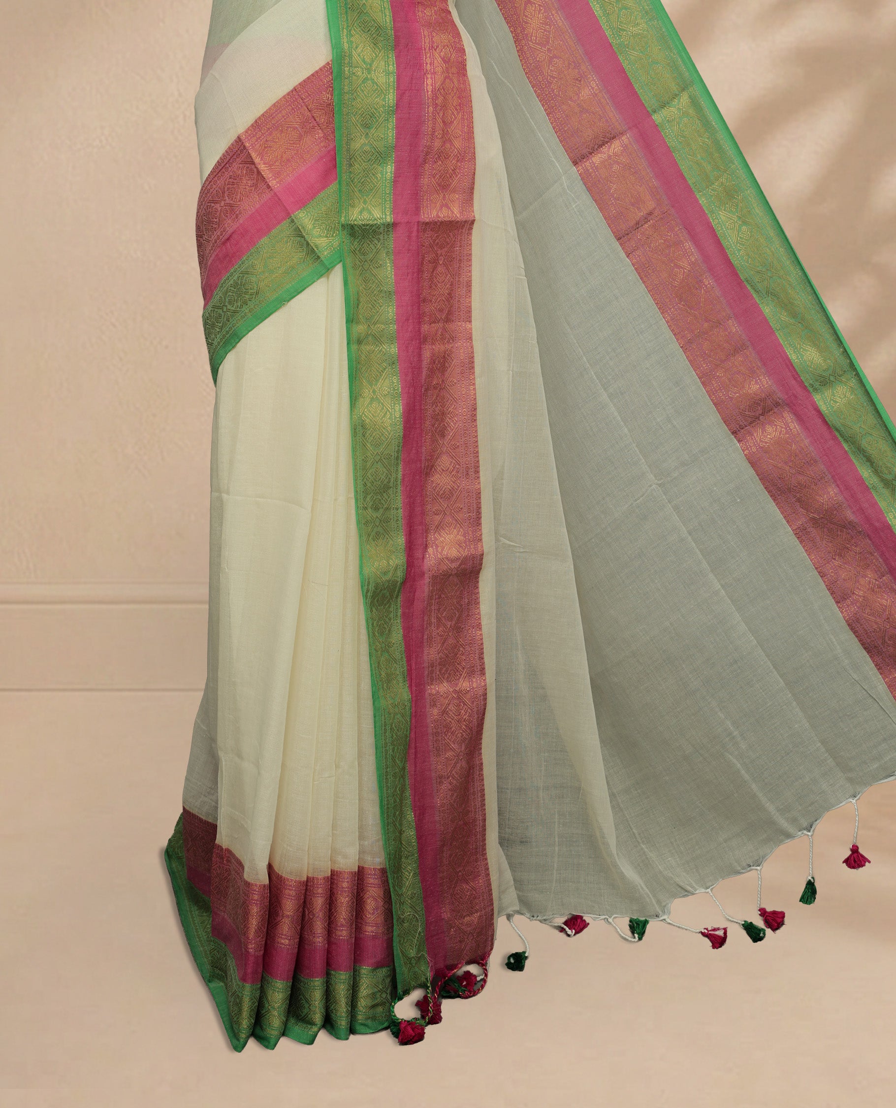 Off white Colour Mul Cotton saree featuring Elegant plain body, contrast Green & Pink colour with gold zari traditional border.