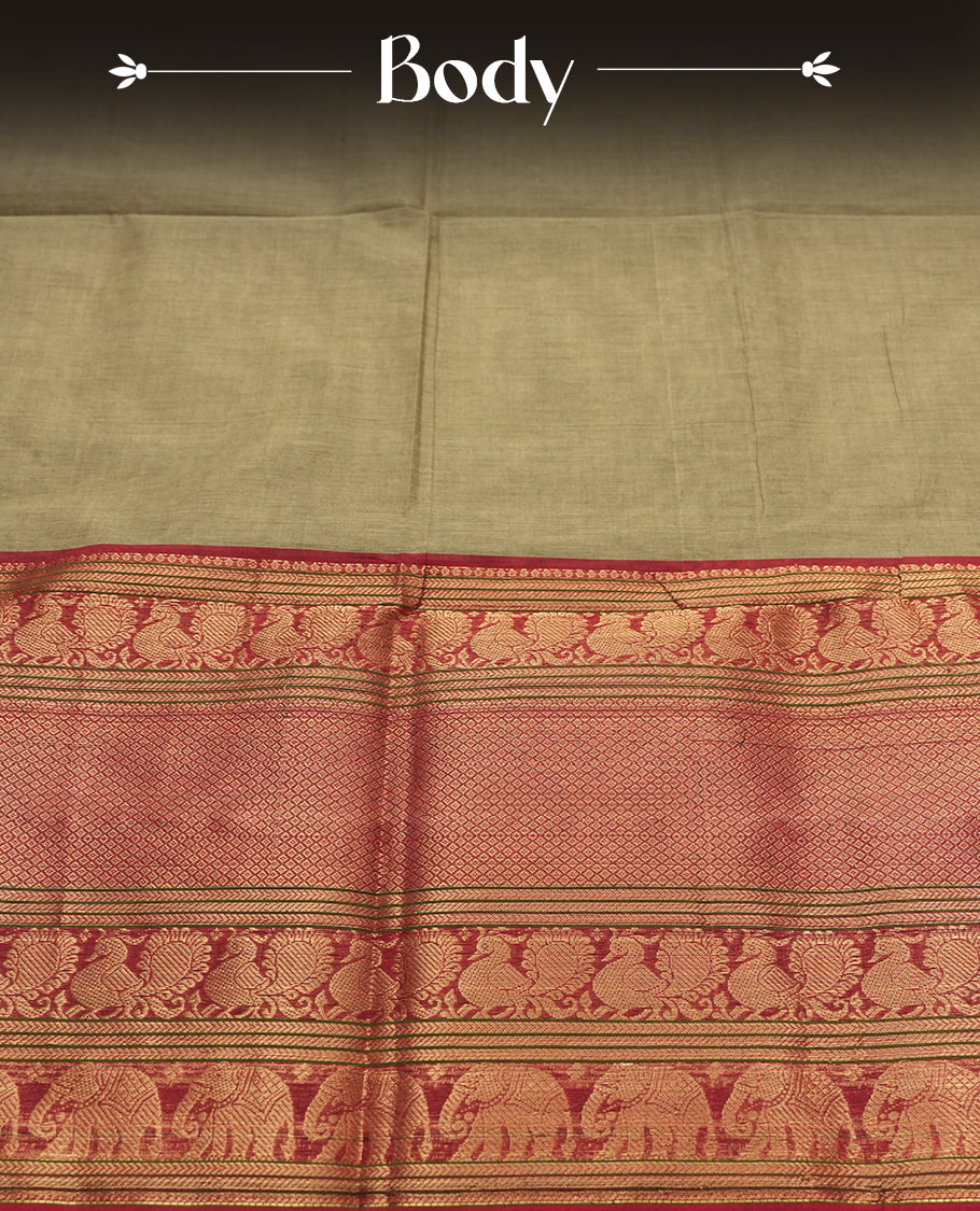 Olive Grey Colour silk cotton saree with broad temple-red zari border featuring peacocks and elephant motifs, subtle gold-striped pallu, and a plain olive grey blouse with the same rich zari border.