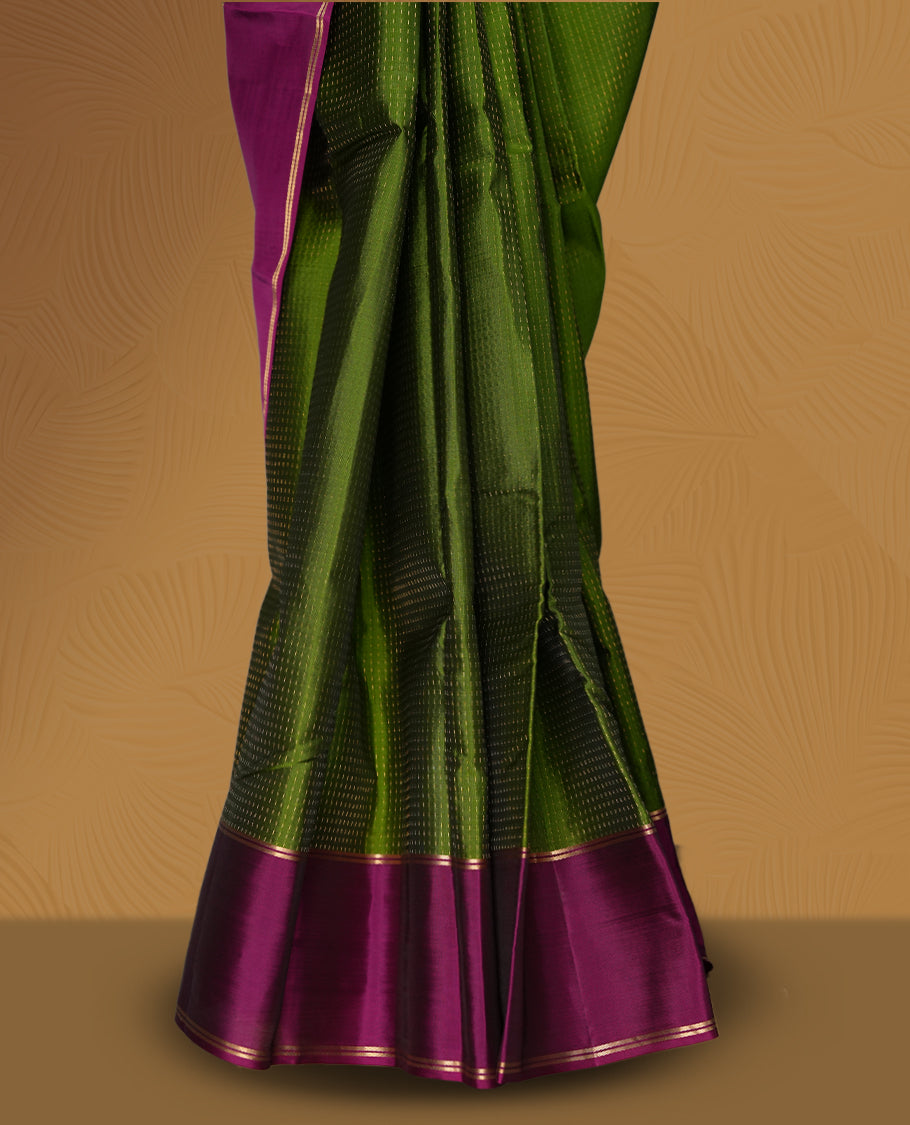 Leaf green colour soft silk saree adorned with intricate self striped, enhanced by a vibrant magenta pink zari border and pallu with rich detailing & paired with a matching blouse.