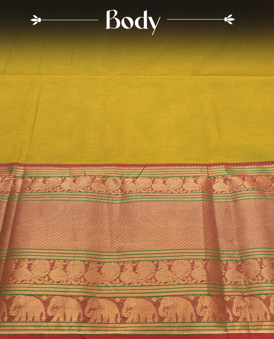 Olive Yellow Colour silk cotton saree with rich temple-red zari border featuring peacocks and elephant motifs, subtle gold-striped pallu, and a coordinated Olive Yellow blouse with matching zari border.