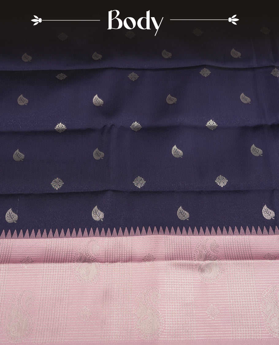Navy blue colour semi silk saree adorned with subtle silver zari motifs on the body, complemented by contrasted a pastel light pink pallu intricately  woven with rich floral patterns border and pallu, and paired with a matching blouse