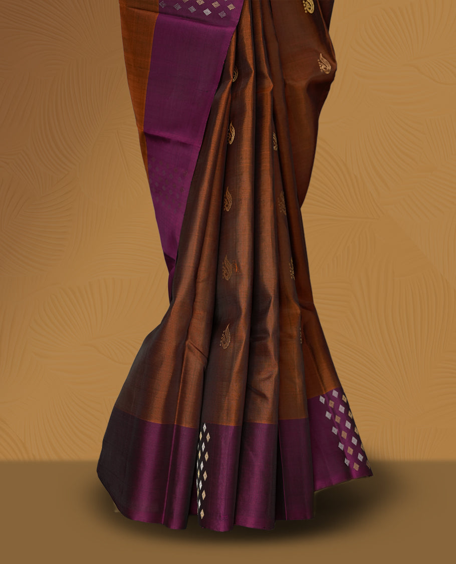 Brown colour soft silk saree adorned with tiny golden buttas, complemented by a rich purple border and pallu with elegant zari designs & Paired with a matching blouse.