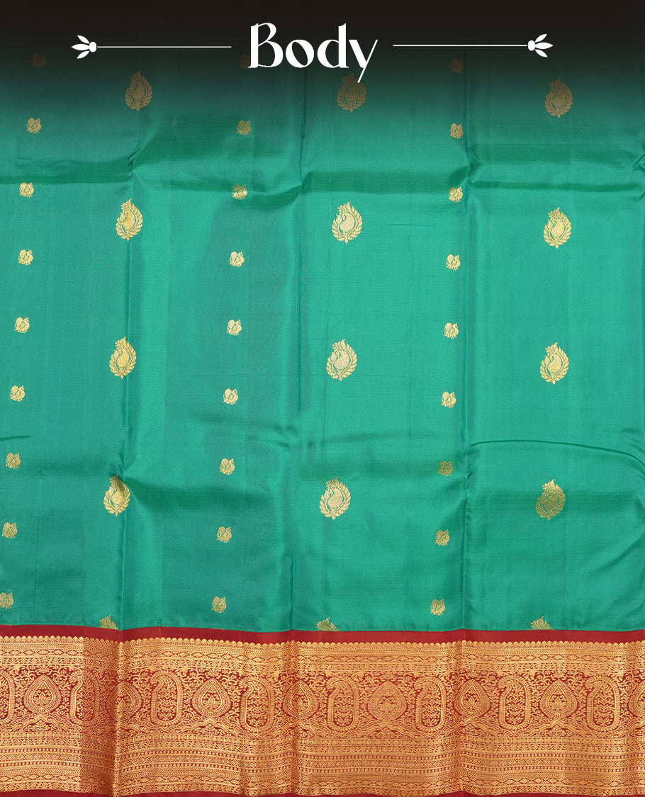 Green colour Vasundhara silk saree adorned with all-over gold mayil motifs on the body, complemented by a  contrast maroon colour with gold traditional border and paired with a matching blouse piece.