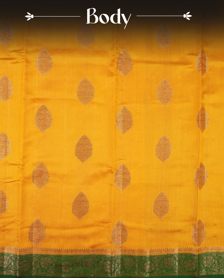 Golden Yellow Colour Banaras Soft Silk Saree with Gold Zari Textured Oval Buttas, Simple Decorative Pallu Border, Grand Pallu with Ornate Floral and Foliate Motifs in Green and Gold Tones, and Matching Forest Green Blouse.