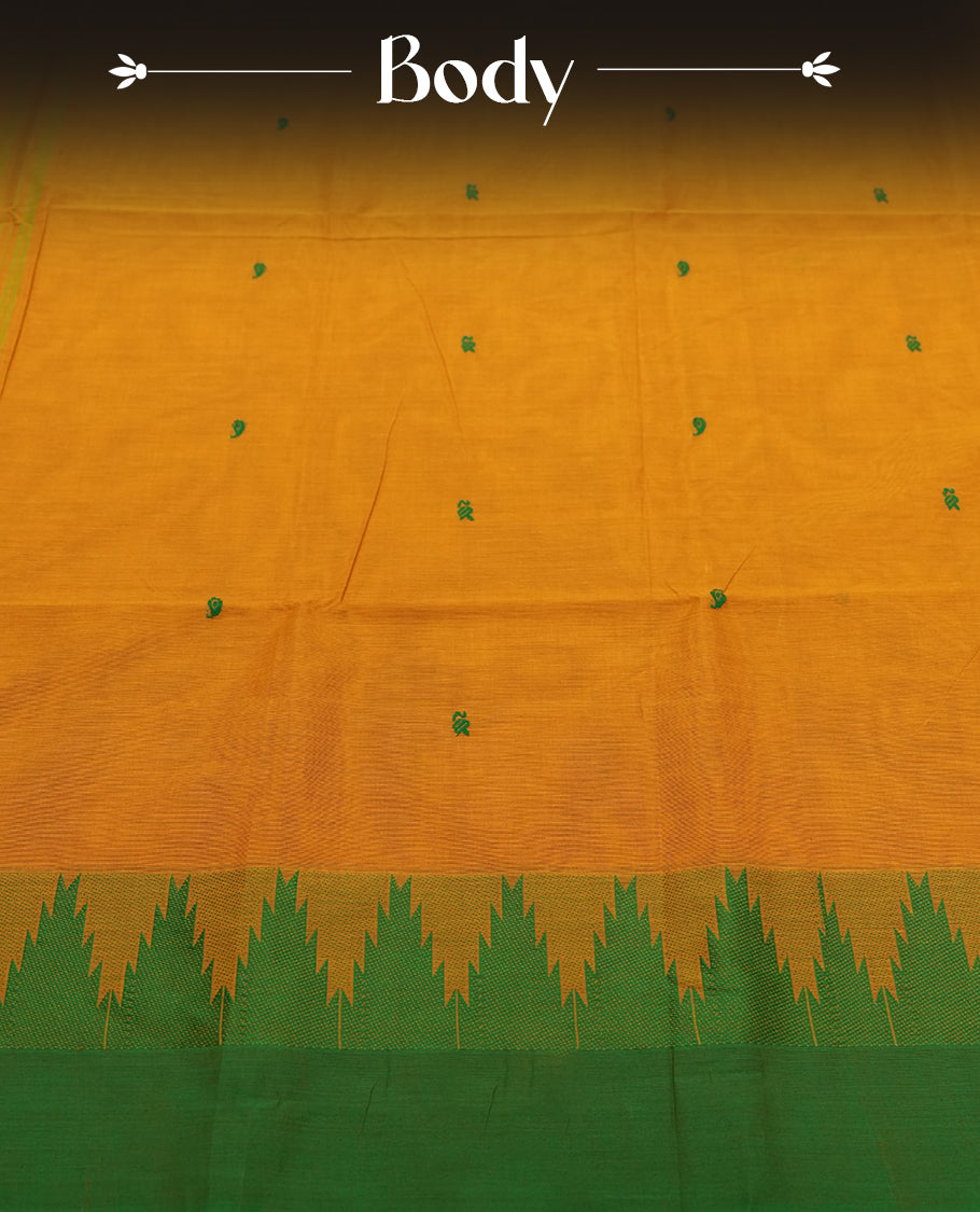 Burnt Mustard Colour silk cotton saree with tiny emerald thread buttas, temple green serrated borders, a pallu lined with green stripes, paired with a plain burnt mustard blouse featuring the same temple green border