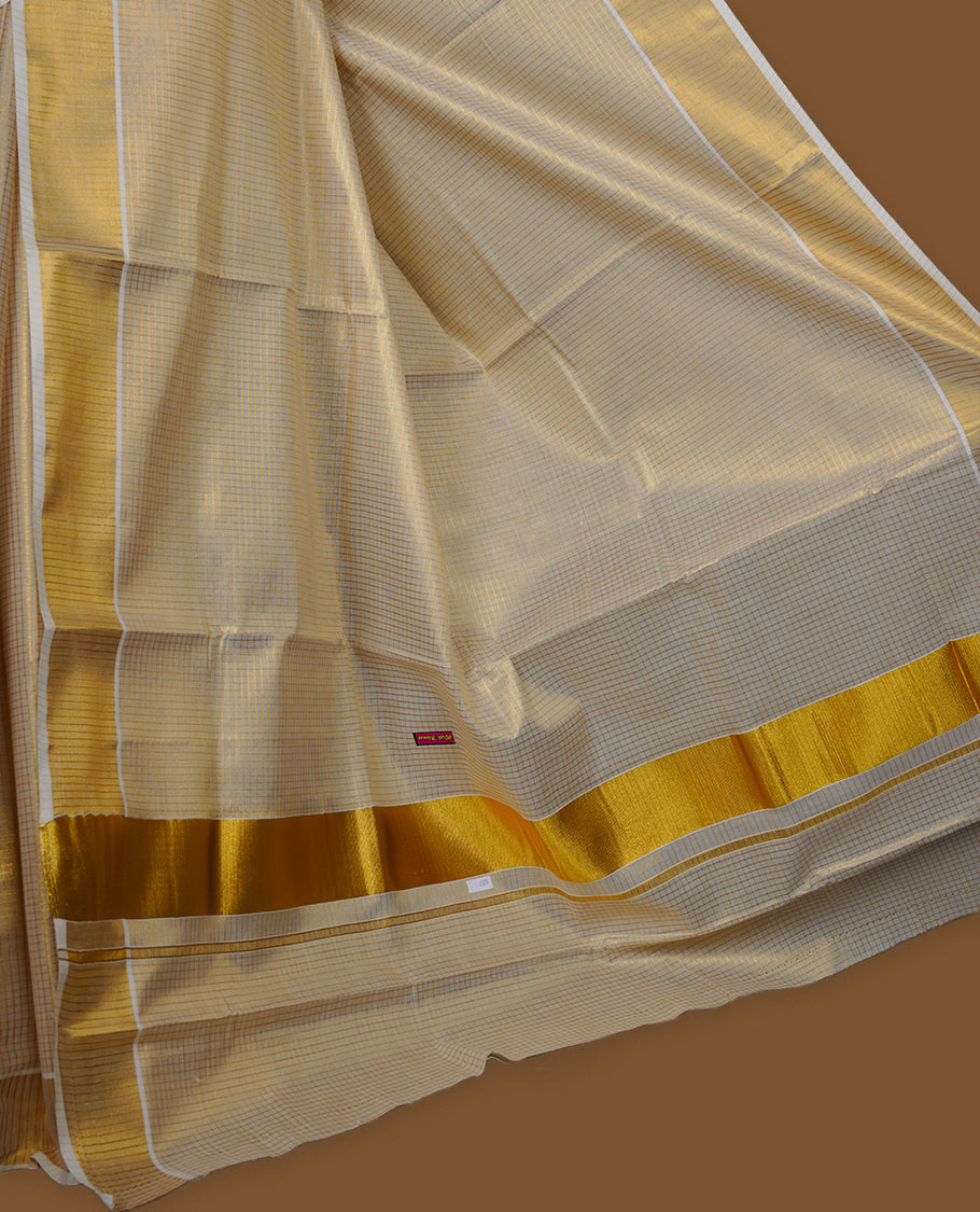 Off-white colour tissue Kerala saree featuring subtle gold checks throughout the body, finished with a classic gold kasavu border and a graceful pallu, paired with a matching blouse.