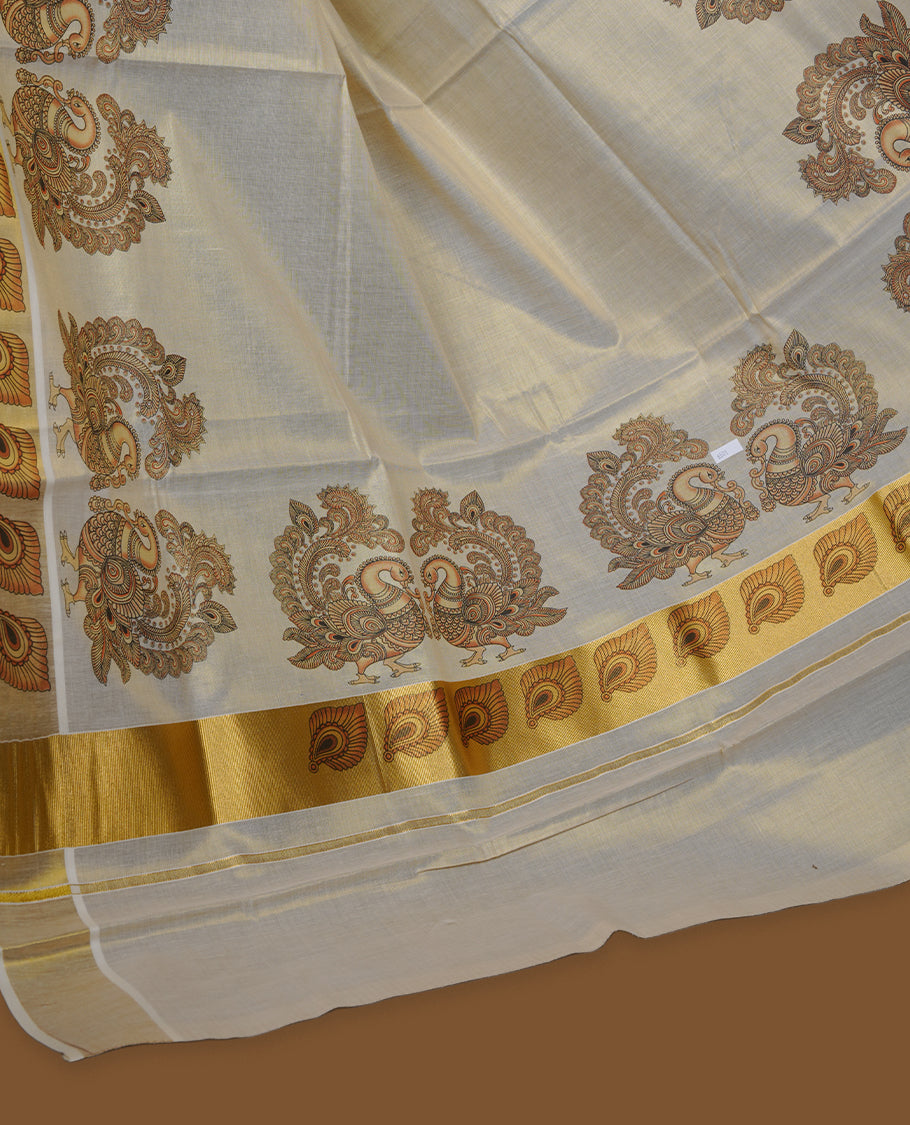 Off-white colour tissue Kerala saree with an elegant gold kasavu border, adorned with antique gold peacock and paisley motifs across the body and pallu, paired with a matching blouse.