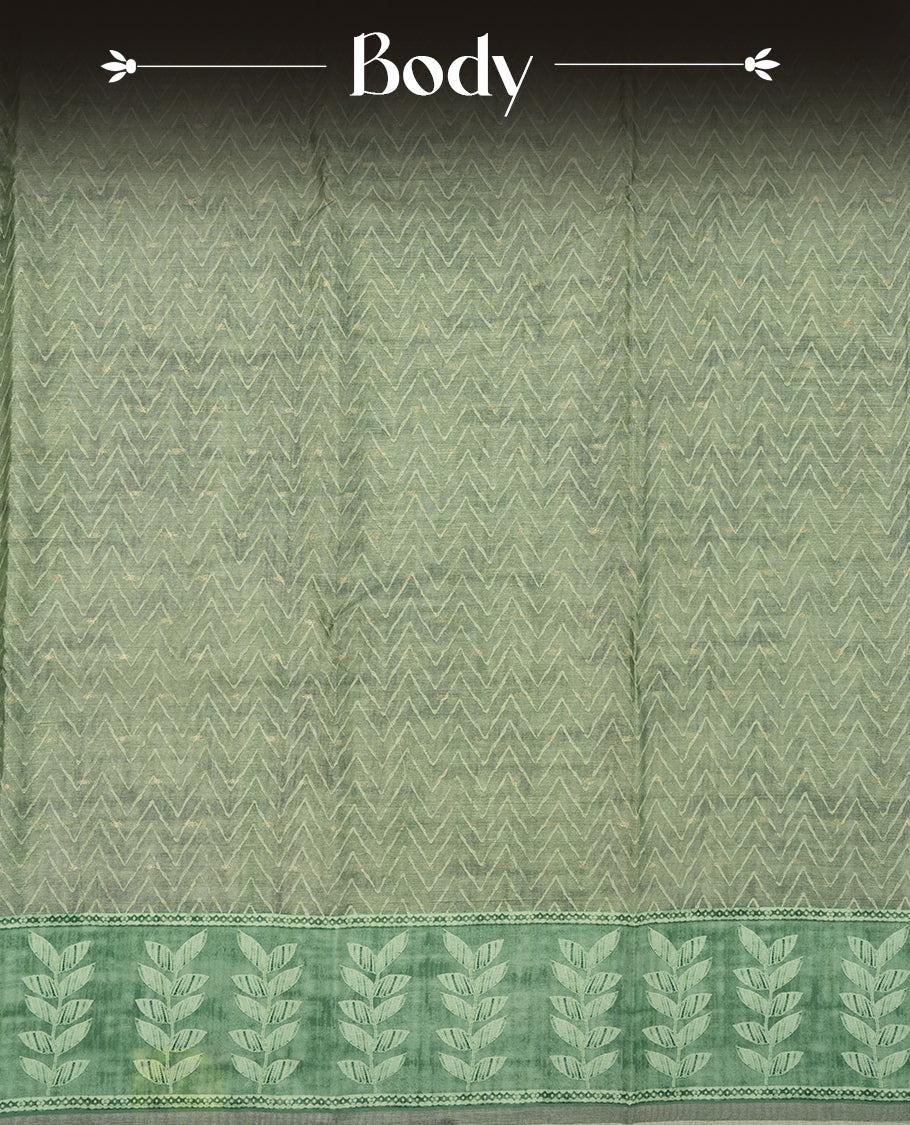 Sage green colour semi tussar saree adorned with Cream Zigzag printed pattern across the body and Leaf pattern on contrast Fern green colour border, paired with a matching blouse.
