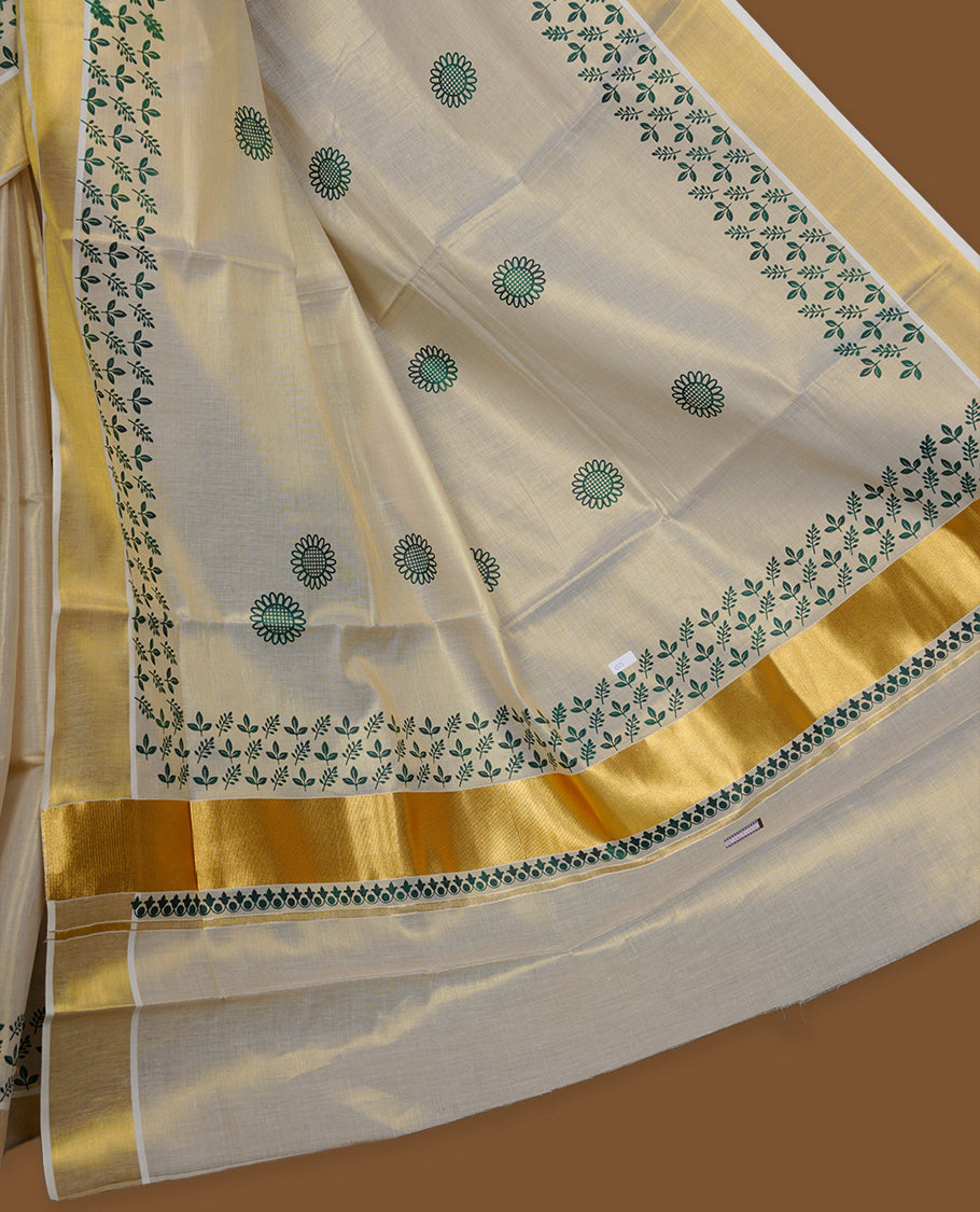 Off-white colour tissue Kerala saree featuring a classic gold kasavu border, highlighted with elegant green leafy and floral motifs across the body and pallu, and paired with a matching blouse.