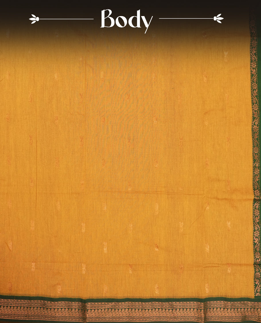 Mustard yellow colour Kalyani Cotton saree with rich green border and pallu, featuring copper zari motifs and intricate weaving & Includes a matching blouse piece.
