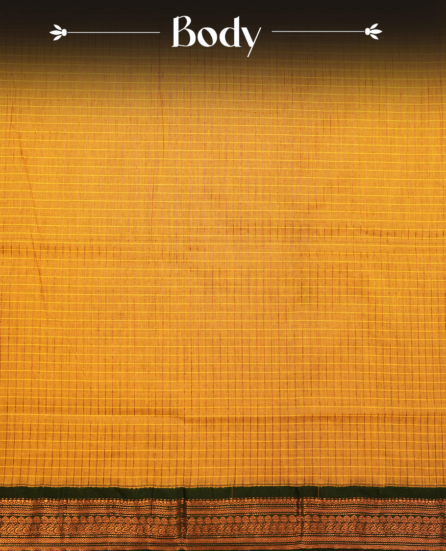 Mustard yellow coloured mixed Kalyani cotton saree featuring copper zari checks on the body, complemented by a dark green coloured border and pallu adorned with copper zari patterns, Paired with a matching blouse.