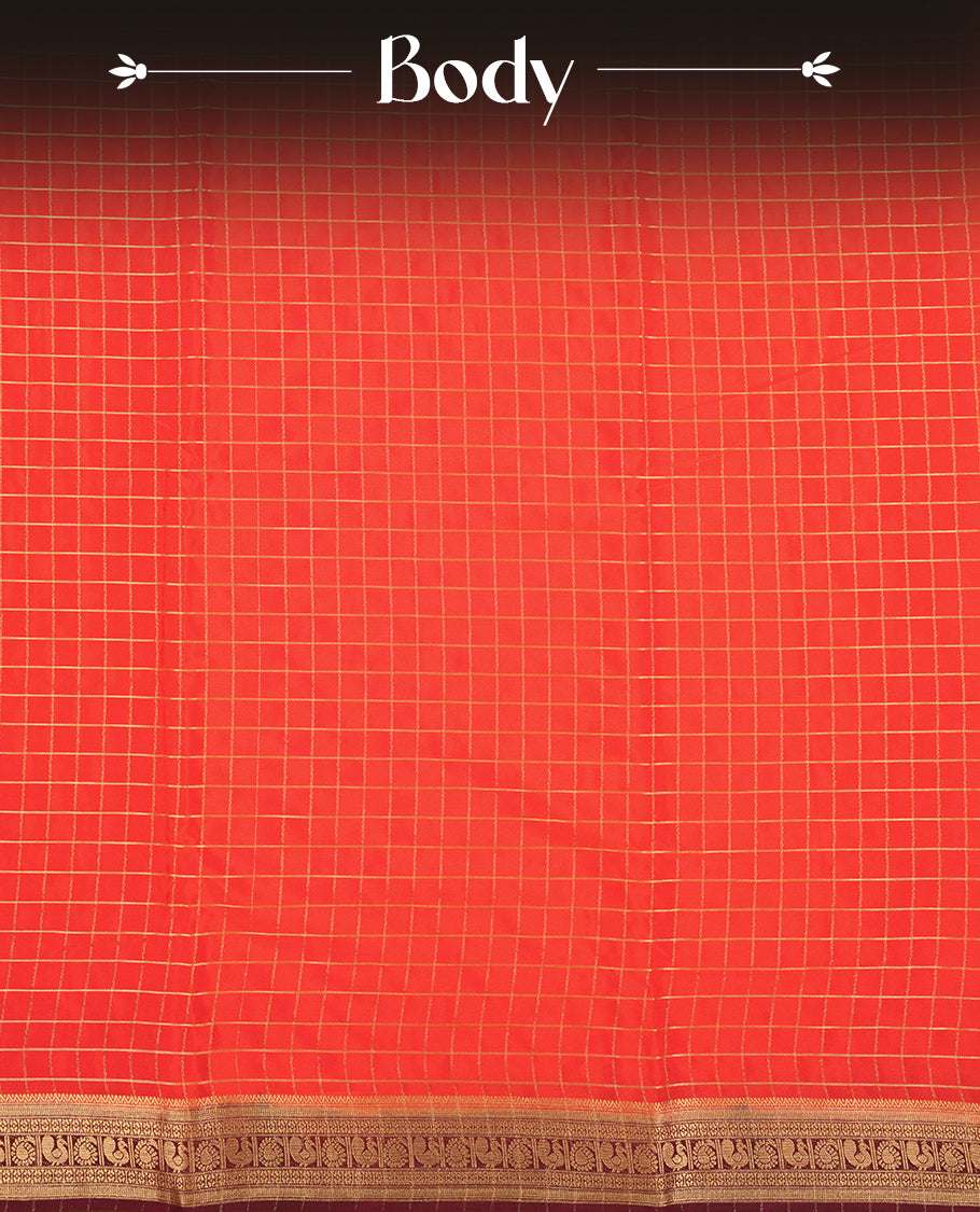 Red colour mysore crepe saree with gold zari check pattern on body, complemented by contrast Brown colour border featuring peacock and chakkram motifs, paired with matching blouse.