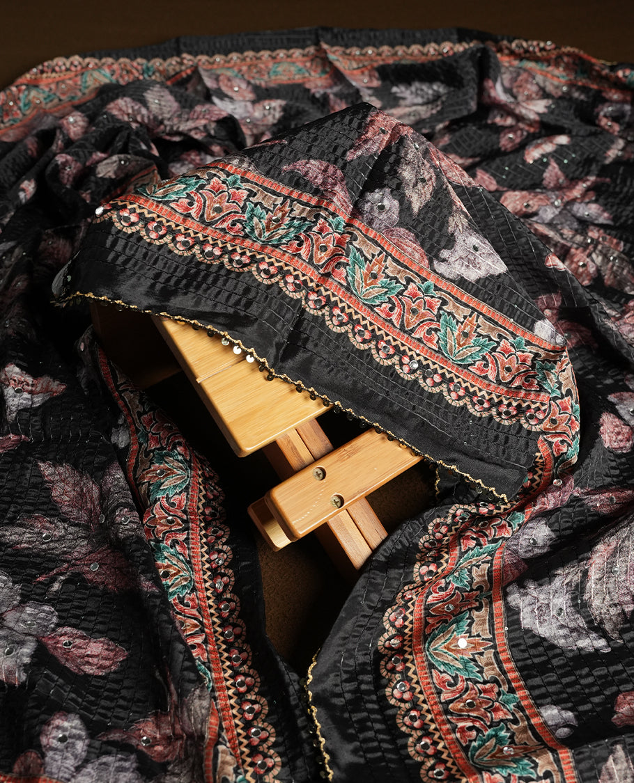 Black colour churidhar material featuring Mirror and thread embroidery, foral print pattern on the self colour front panel, floral digital printed dupatta with elegant border, and matching plain bottom