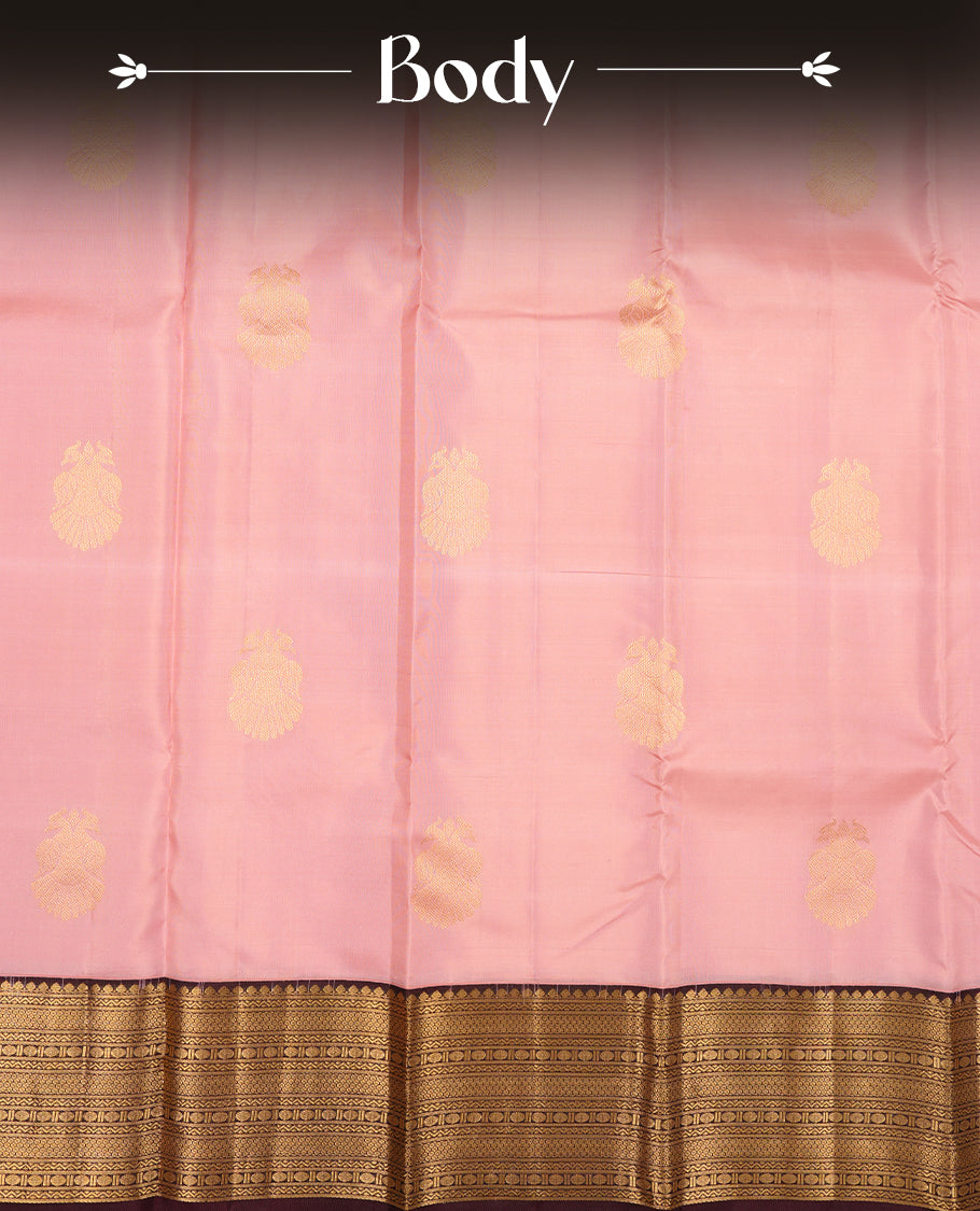 Baby pink colour Vasundhara silk saree adorned with all-over gold two head mayil motifs on the body, complemented by a  contrast brown colour with gold traditional border and paired with a matching blouse piece.